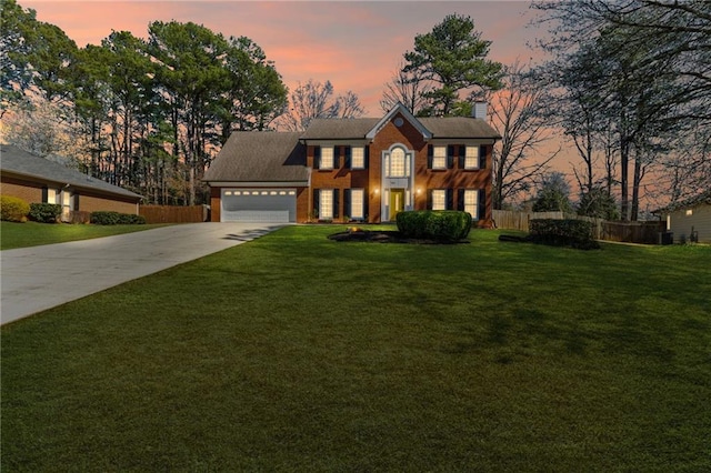 colonial-style house with a garage, a lawn, driveway, and fence