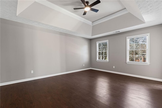 spare room with dark wood-style floors, baseboards, visible vents, ceiling fan, and a raised ceiling