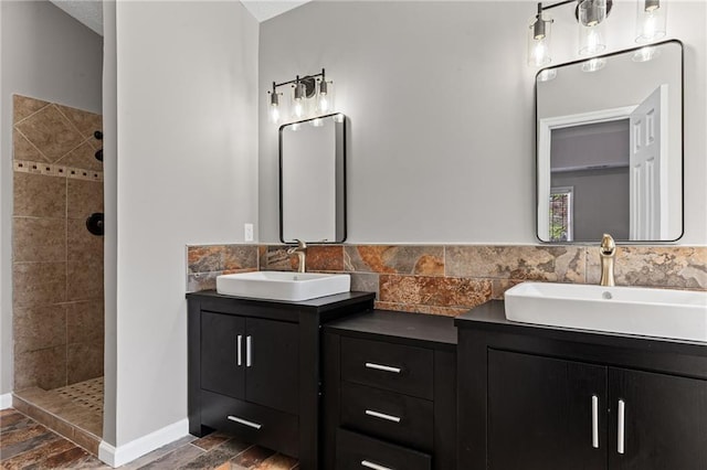 full bathroom featuring a sink, tiled shower, and double vanity