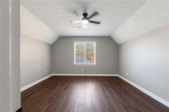 bonus room with vaulted ceiling, visible vents, baseboards, and dark wood-style flooring