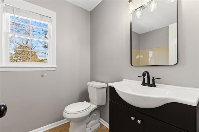 bathroom featuring baseboards, toilet, wood finished floors, and vanity