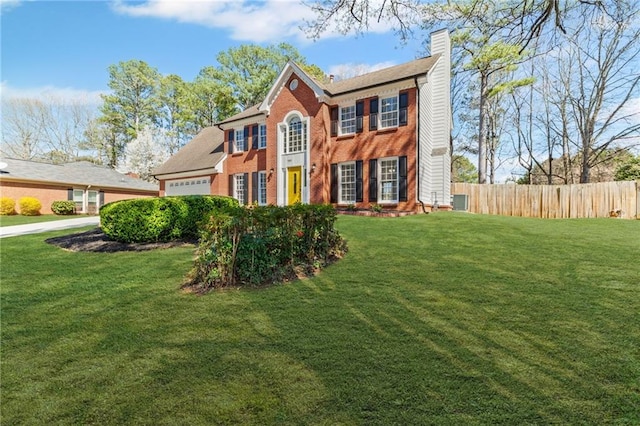 colonial home with brick siding, an attached garage, a front lawn, and fence