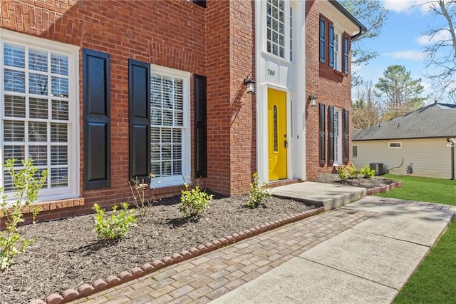 doorway to property featuring brick siding and central AC