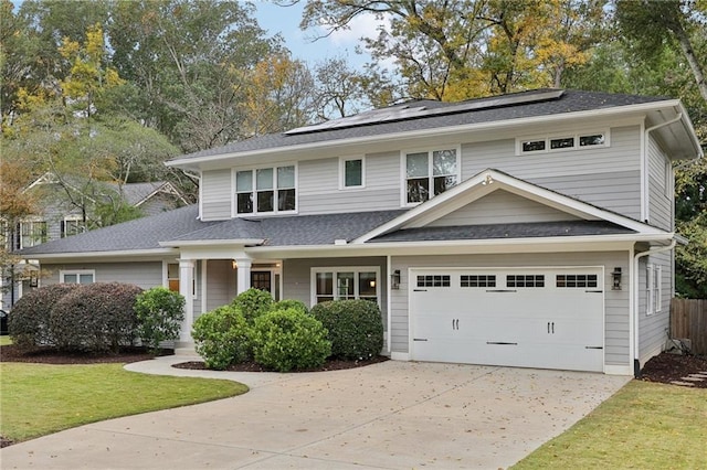 view of front facade featuring solar panels, an attached garage, a shingled roof, concrete driveway, and a front lawn