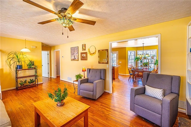 living room with ceiling fan, wood-type flooring, and a textured ceiling