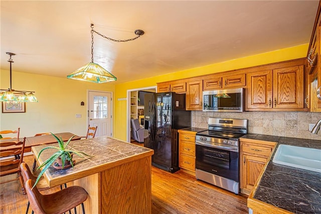 kitchen featuring sink, decorative light fixtures, a breakfast bar area, and appliances with stainless steel finishes