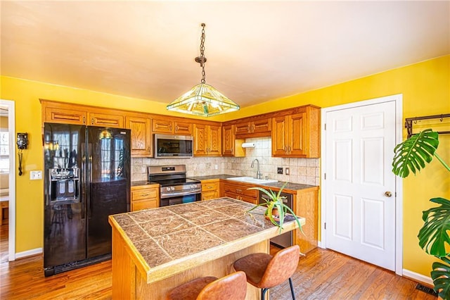 kitchen with pendant lighting, sink, a breakfast bar area, decorative backsplash, and stainless steel appliances