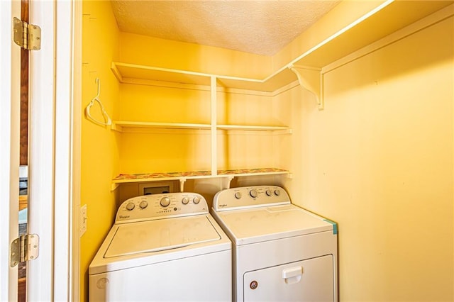 laundry area with washing machine and dryer and a textured ceiling