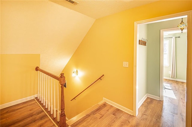 staircase with lofted ceiling and hardwood / wood-style floors