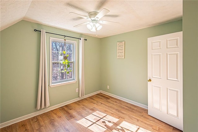 spare room featuring vaulted ceiling, ceiling fan, light hardwood / wood-style floors, and a textured ceiling