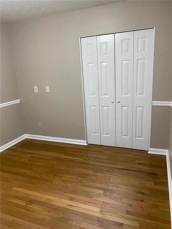 unfurnished bedroom featuring a textured ceiling, hardwood / wood-style flooring, and a closet