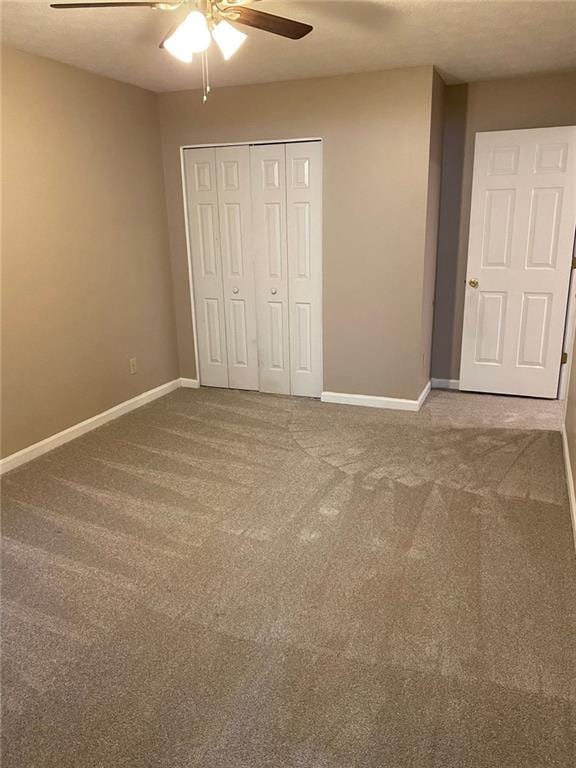 unfurnished bedroom with ceiling fan, a closet, and carpet