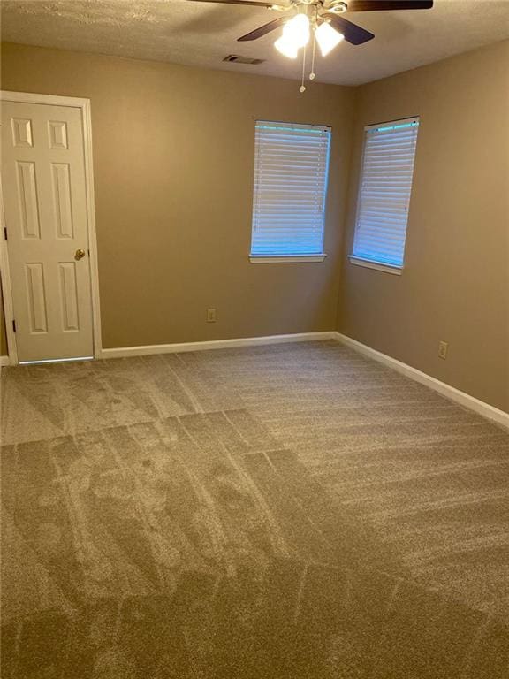 carpeted spare room featuring ceiling fan and a textured ceiling