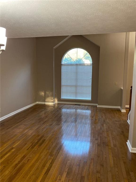 empty room featuring dark hardwood / wood-style flooring, a textured ceiling, and an inviting chandelier