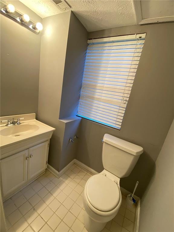 bathroom with vanity, toilet, a textured ceiling, and tile patterned flooring