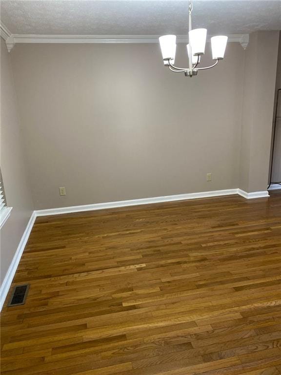 empty room featuring ornamental molding, dark hardwood / wood-style floors, and a chandelier