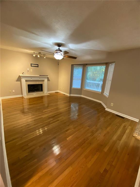 unfurnished living room featuring hardwood / wood-style flooring and ceiling fan