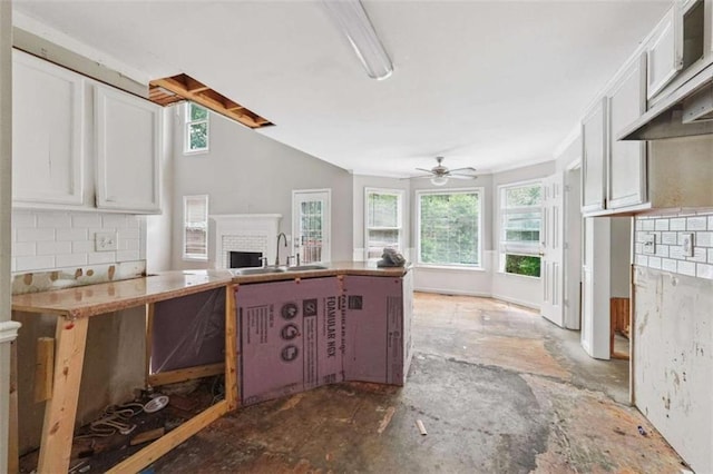 4467 Boatmans Cv, Stone Mountain, GA 30083 - kitchen with backsplash, white cabinets, a brick fireplace, a ceiling fan, and open floor plan