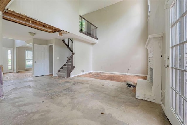 4467 Boatmans Cv, Stone Mountain, GA 30083 - unfurnished living room with a fireplace, a towering ceiling, stairs, and concrete floors