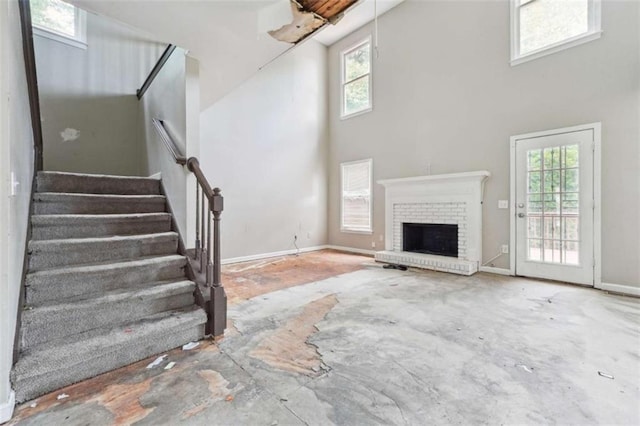 4467 Boatmans Cv, Stone Mountain, GA 30083 - unfurnished living room featuring a high ceiling, healthy amount of natural light, a brick fireplace, and stairs