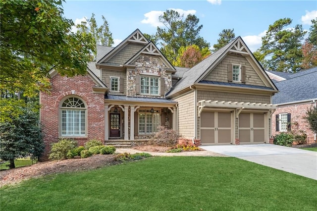 craftsman inspired home with covered porch, a front yard, and a garage