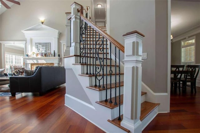 staircase with plenty of natural light, dark wood-type flooring, ornate columns, and ornamental molding