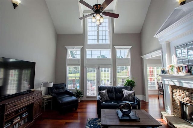 living room featuring dark hardwood / wood-style floors, a fireplace, ceiling fan, and high vaulted ceiling