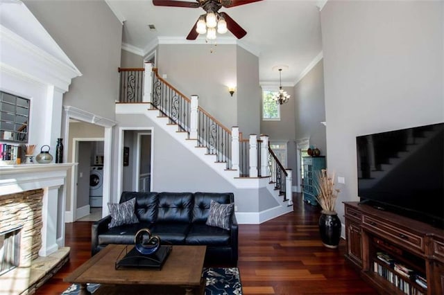 living room featuring a stone fireplace, crown molding, dark hardwood / wood-style floors, and ceiling fan with notable chandelier