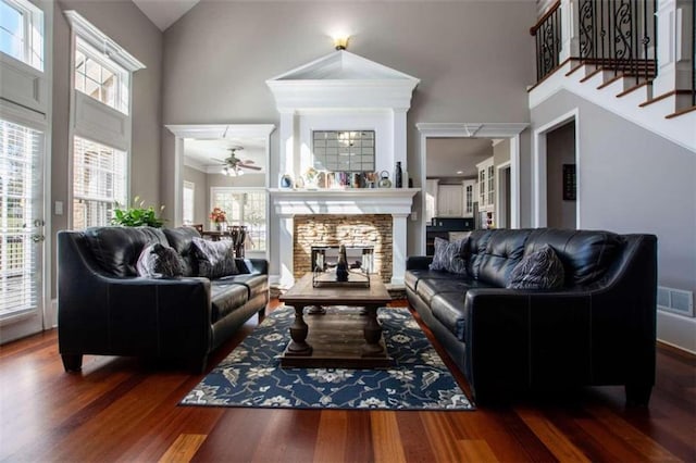 living room featuring a multi sided fireplace, plenty of natural light, dark hardwood / wood-style floors, and a towering ceiling