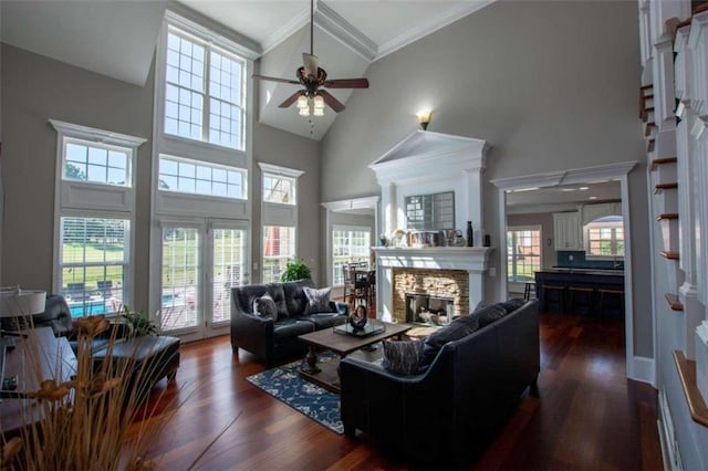 living room with crown molding, ceiling fan, dark hardwood / wood-style floors, a stone fireplace, and high vaulted ceiling