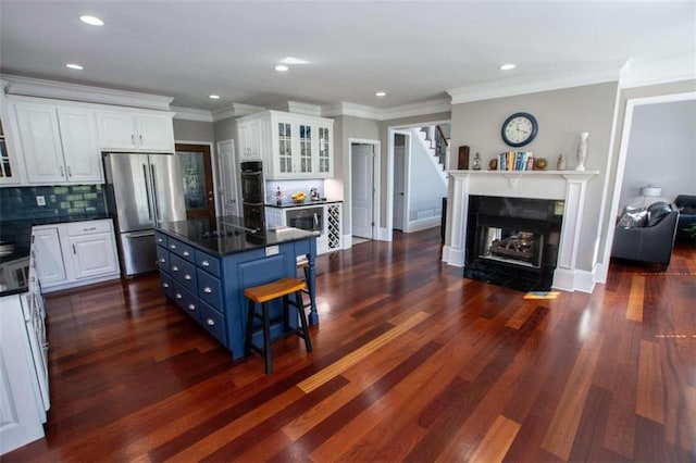 kitchen with white cabinetry, stainless steel refrigerator, dark hardwood / wood-style flooring, blue cabinetry, and decorative backsplash