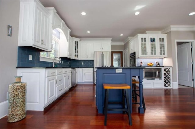 kitchen with appliances with stainless steel finishes, white cabinets, decorative backsplash, and dark wood-type flooring