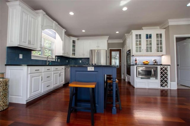 kitchen with white cabinetry, tasteful backsplash, dark wood-type flooring, a kitchen island, and appliances with stainless steel finishes