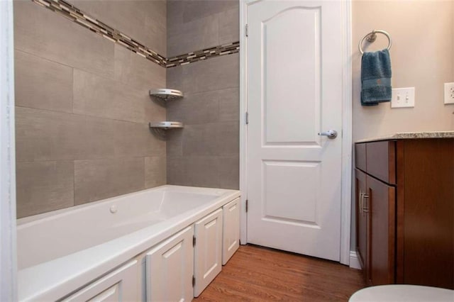 full bathroom featuring hardwood / wood-style flooring, toilet, tiled shower / bath combo, and vanity