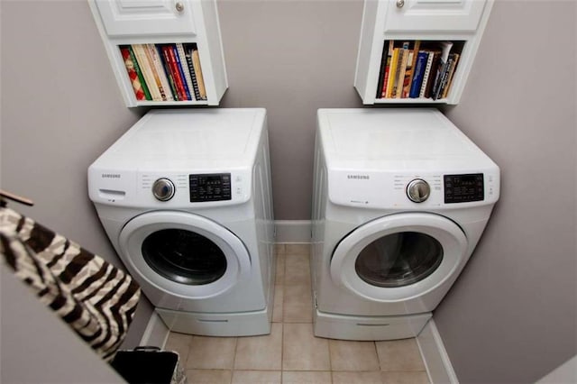 clothes washing area with cabinets, light tile patterned floors, and independent washer and dryer