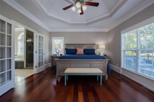 bedroom with multiple windows, hardwood / wood-style flooring, and a tray ceiling