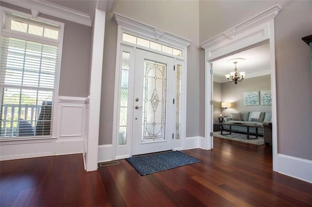 foyer entrance with dark hardwood / wood-style floors, crown molding, a chandelier, and plenty of natural light