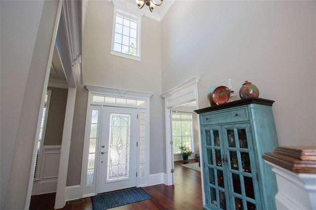 entryway with ornamental molding, a towering ceiling, and dark wood-type flooring