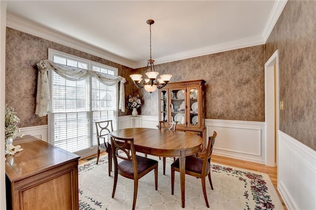 dining space featuring a wainscoted wall, wallpapered walls, and an inviting chandelier