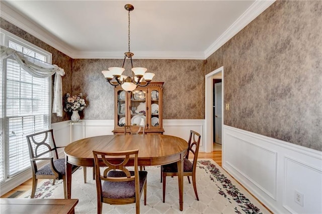 dining space with a notable chandelier, a wainscoted wall, and light wood-type flooring