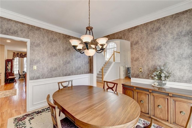 dining room with a notable chandelier, wallpapered walls, and a wainscoted wall