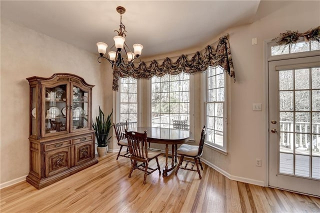 dining room with light wood-style flooring, baseboards, and a chandelier