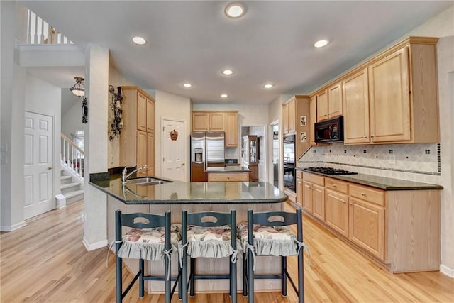 kitchen with black appliances, light brown cabinets, a sink, backsplash, and a peninsula