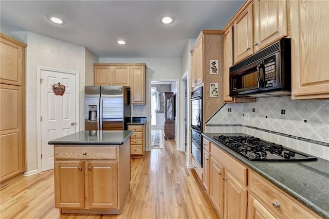 kitchen featuring light brown cabinetry, a center island, black appliances, and light wood-style floors