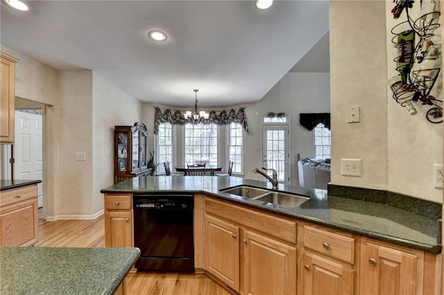 kitchen with dark stone counters, light wood-style flooring, a sink, dishwasher, and a chandelier