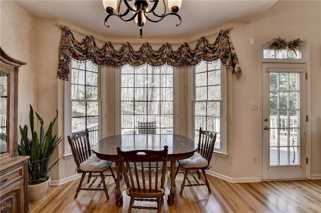 dining room featuring a notable chandelier, baseboards, and light wood-style floors