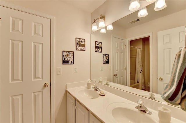 bathroom featuring double vanity, visible vents, toilet, and a sink