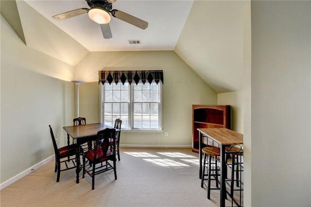 carpeted dining space with visible vents, baseboards, a ceiling fan, and vaulted ceiling