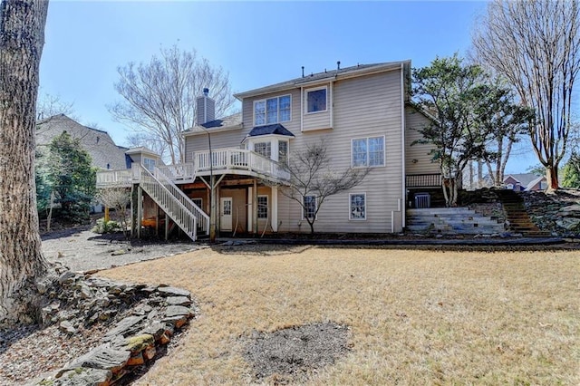 rear view of property featuring a lawn, a chimney, stairs, and a deck