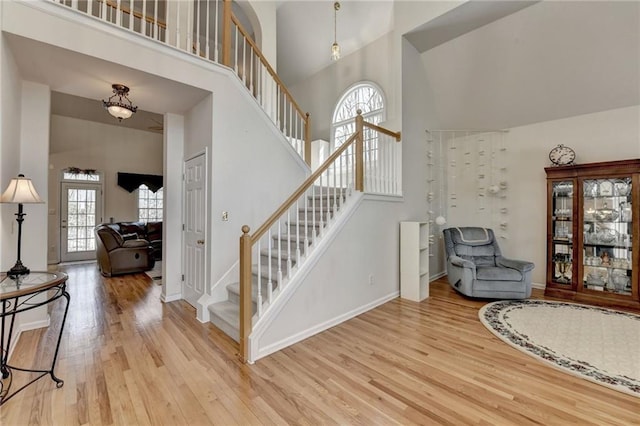 staircase featuring baseboards, a towering ceiling, and wood finished floors